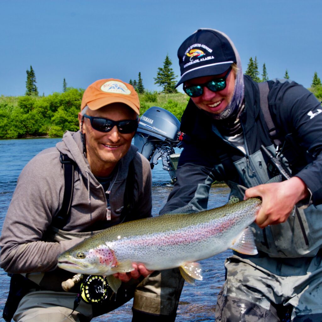 Fishing guide and client holding a rainbow trout on a fishing trip in montana