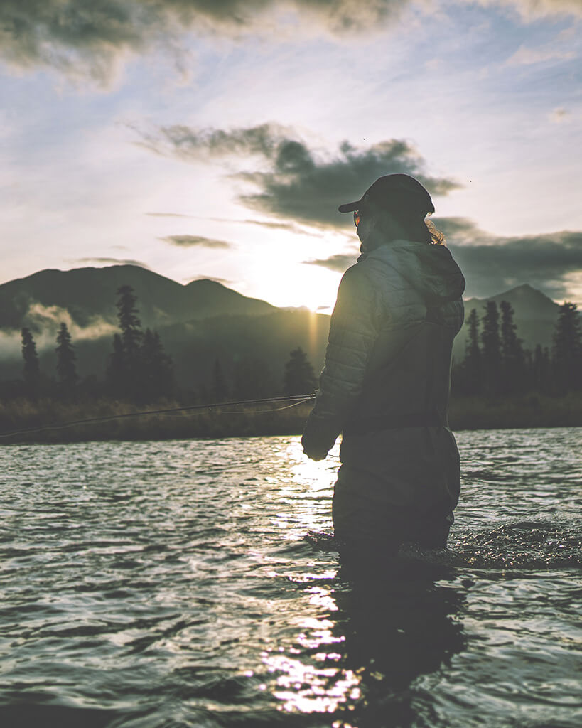 Lodge Guest standing in the water fishing at sunrise